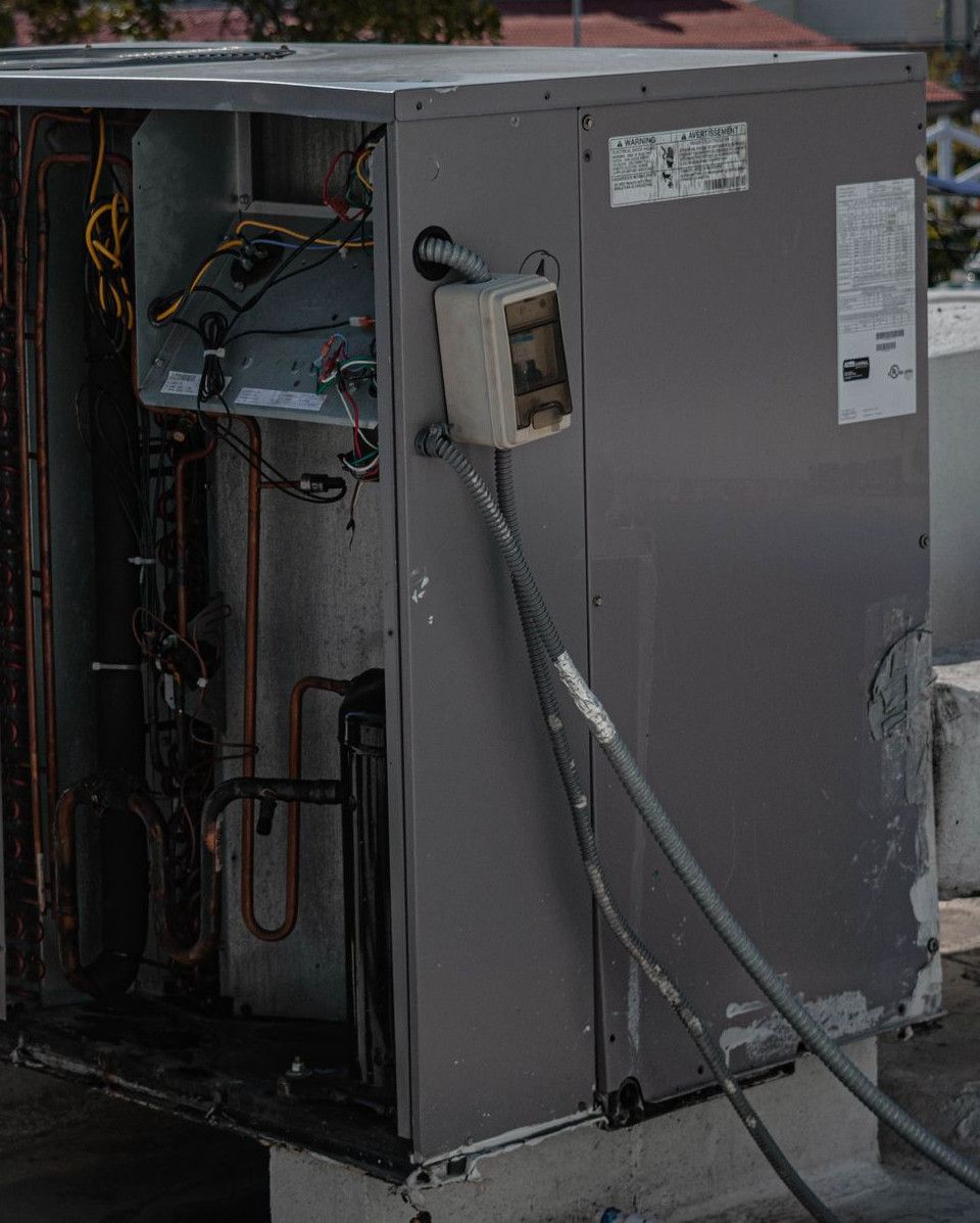 A technician is repairing an air conditioning unit on a rooftop, demonstrating skilled manual work.
