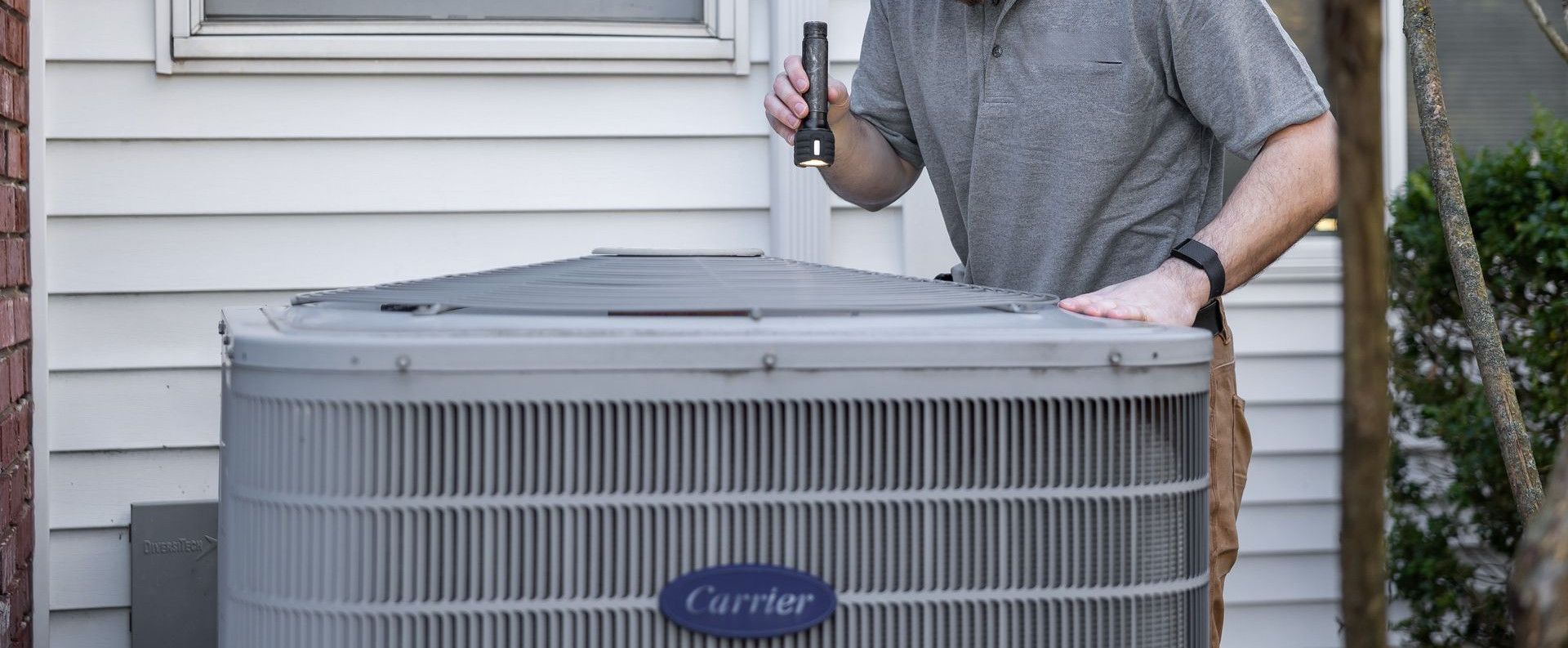 A technician inspects an outdoor HVAC unit for maintenance.